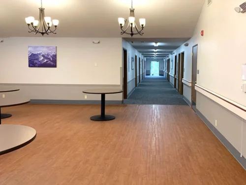 Hallway with wooden flooring, chandeliers, round tables, and multiple doors along the corridor